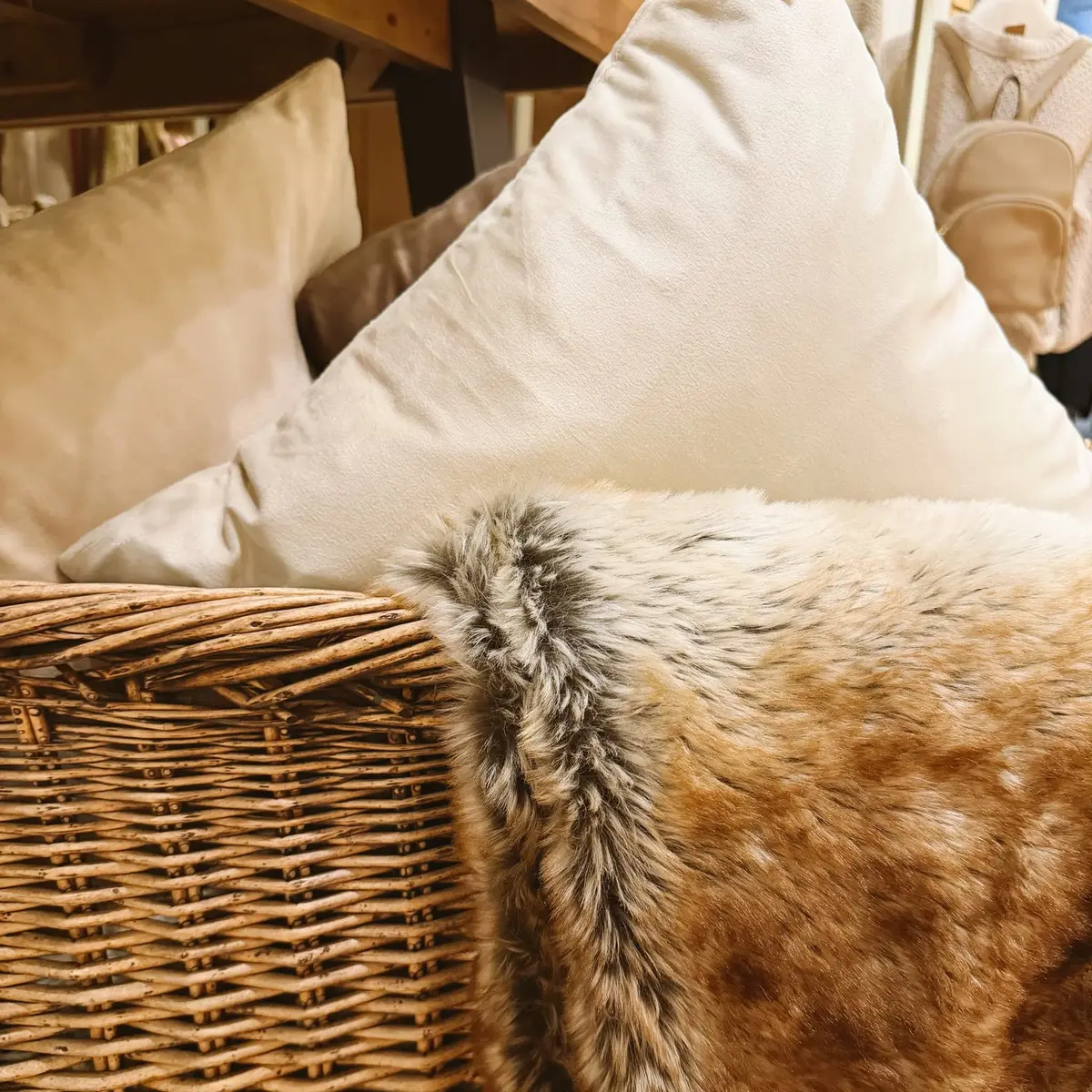 Cream pillows and a faux-fur throw tucked into a woven basket